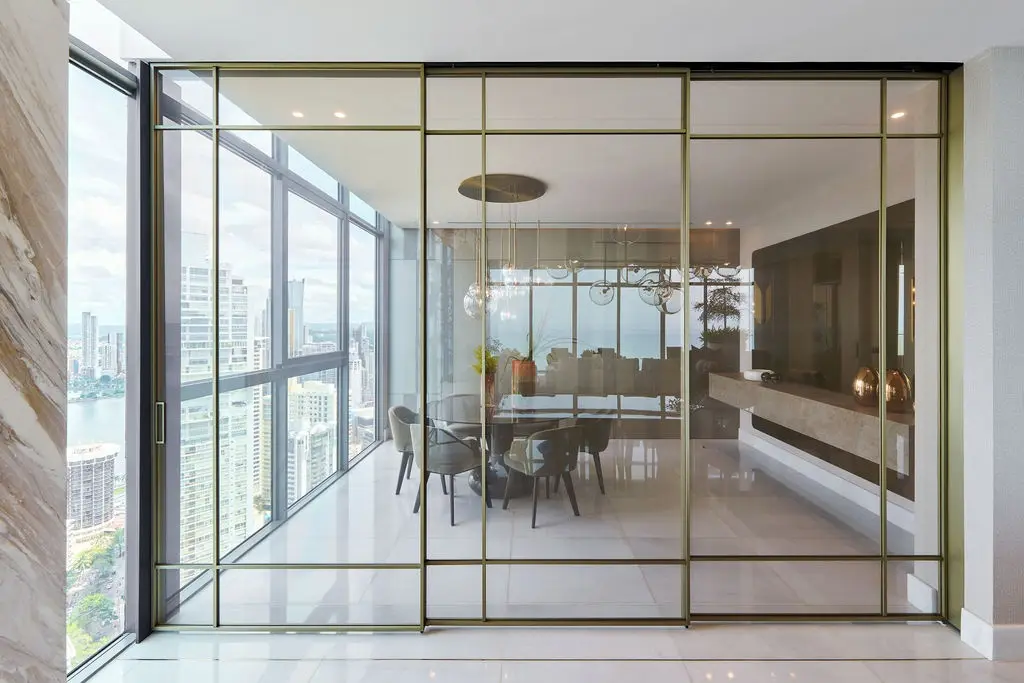 Proyecto Seacat — puertas corredizas de perfil dorado con vidrio tejido, Pernia Glass